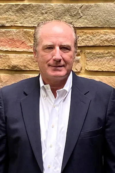 A man in a suit and tie standing next to a brick wall.